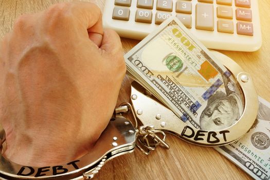 Problems with debt. Hand in handcuffs and money.
