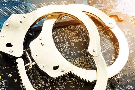 Handcuffs and electronic devices. Cyber crime or fraud.