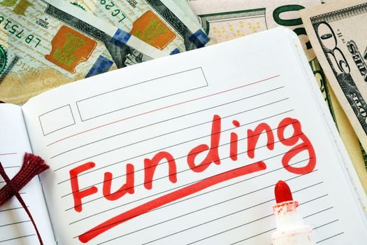 Hand is writing Funding in the note.
