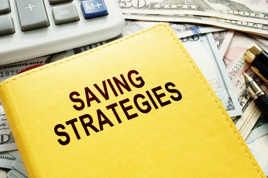 Book with name Saving Strategies, calculator and money.