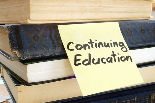 Memo stick with words Continuing education and books.