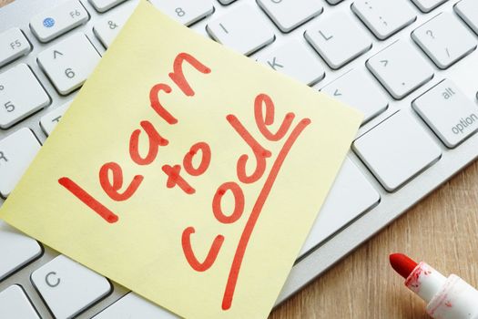 Learn to code written on a memo stick and keyboard.