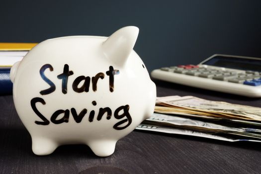 Start Saving written on a piggy bank and money.