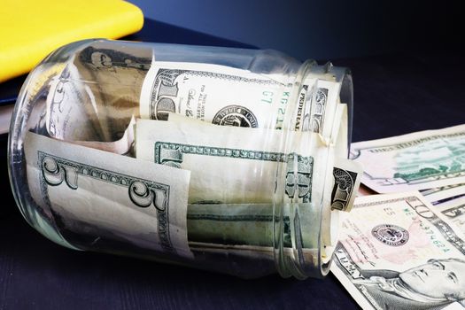 Savings. Jar with money. Dollar banknotes on a desk.