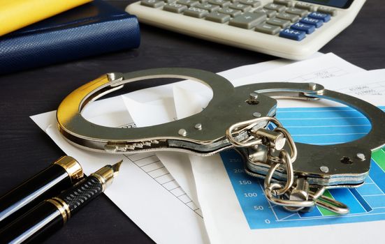 Financial fraud concept. Business documents and handcuffs.