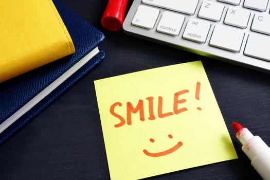 Memo stick with sign Smile in an office. Inspiration.