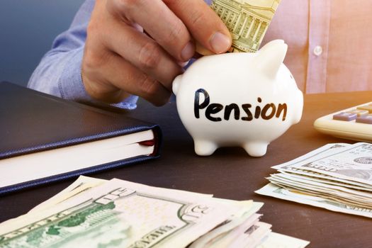 Retirement plan. Man is putting dollar banknote in a piggy bank with sign pension.