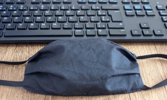 Mask next to a office keyboard on top of a desk, as a new daily item to use because COVID-19