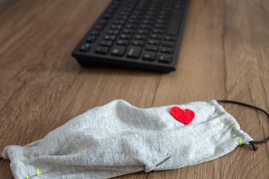 Mask next to a office keyboard on top of a desk, as a new daily item to use because COVID-19