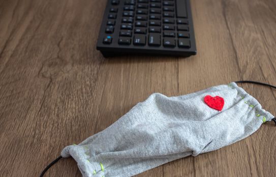 Mask next to a office keyboard on top of a desk, as a new daily item to use because COVID-19