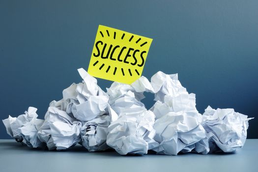 Stack of paper balls as symbol of failure and word success on top.