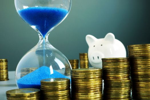 Sand clock, piggy bank and money. Bank deposit and savings.