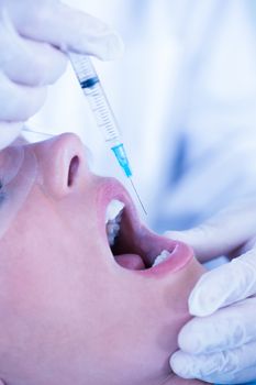 Close up of a patient with mouth open and syringe for injection at the dental clinic