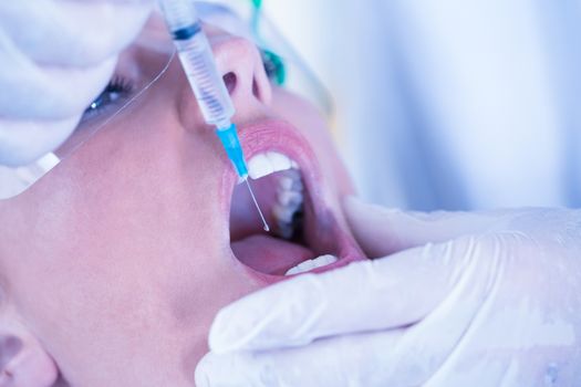 Close up of a patient with mouth open and syringe for injection at the dental clinic