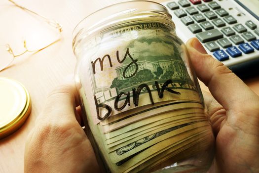 Jar with dollars and sign my bank on a side. Home finances and savings concept.