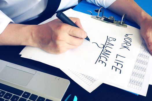 Man is writing words work life balance.