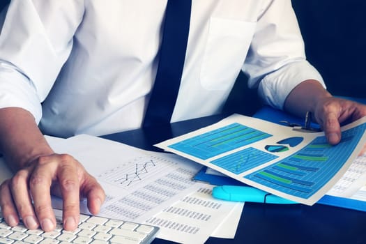 Businessman working with computer and financial business documents at office.