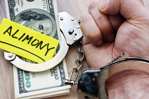 Alimony and hand in handcuffs. Legal separation.