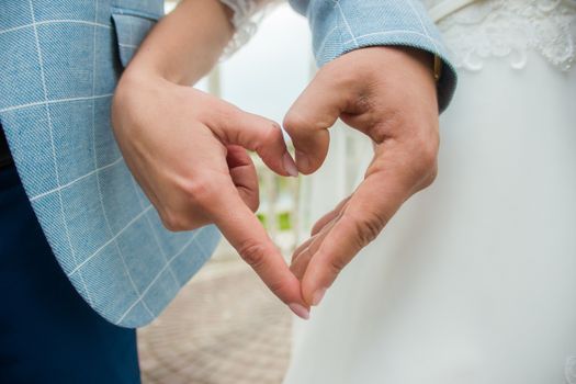 Hands of newlyweds show a symbol of heart and love.