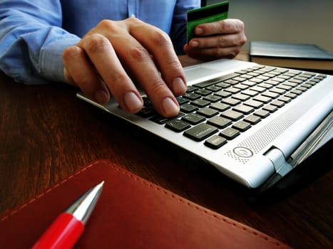 Man makes online purchase uses laptop and credit card for buying in internet.