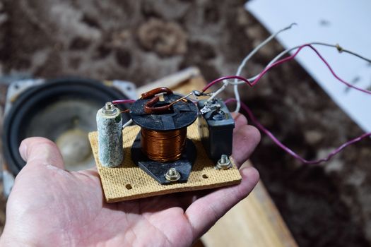 Acoustic filter in a music column. Electrical circuit of a magnetic coil, capacitor and resistance. Repair of acoustic dynamics, ration soldering wire on the speaker.