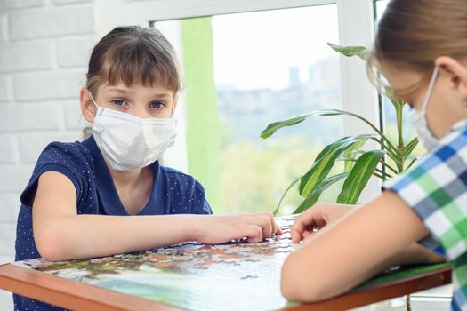 A girl in a medical mask plays board games and looked into the frame.