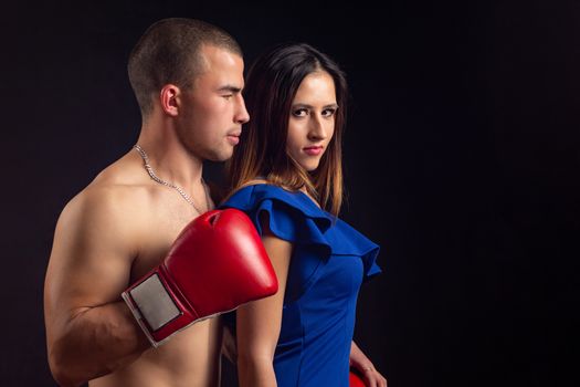 Boxer hugs slender girl on black background