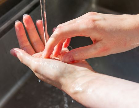 Woman washing hands with soap to prevent germs, bacteria and avoid coronavirus infections