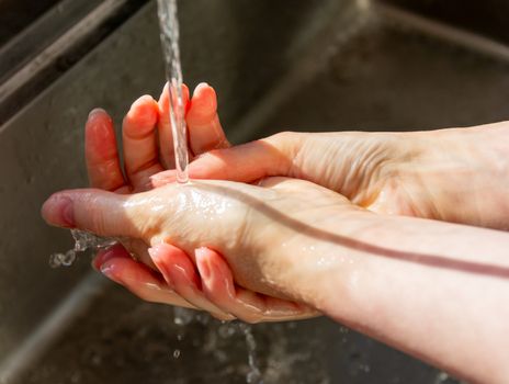 Woman washing hands with soap to prevent germs, bacteria and avoid coronavirus infections