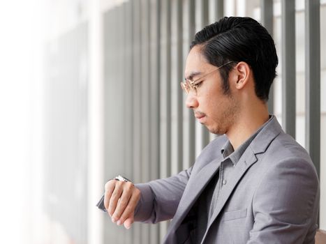 Asian business man in formalwear waiting for his appointment at the walkway.