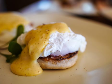 Eggs Benedict, a traditional American breakfast that consists of two halves of an English muffin topped with a poached egg, bacon or ham, and hollandaise sauce.