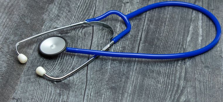 A blue medical stethoscope isolated on a wooden table.
