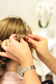 Professional services in the hairdressing salon  - a young woman with beautiful blonde hair has made hairstyles for a wedding party.
