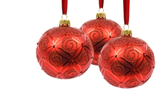 Perfect and ideal three red Christmas balls hanging on a red ribbon on a white background in close-up