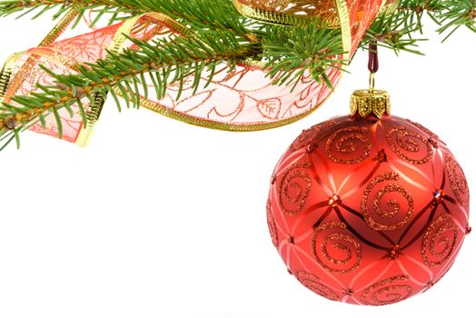 Red glass ball hanging on a spruce twig decorated with red ribbon on a white background with copy place