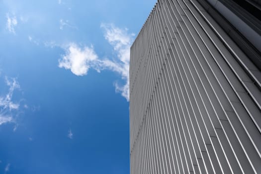 Composite image of a modern architecture background - metal skyscraper on a blue sky background and cumulus clouds