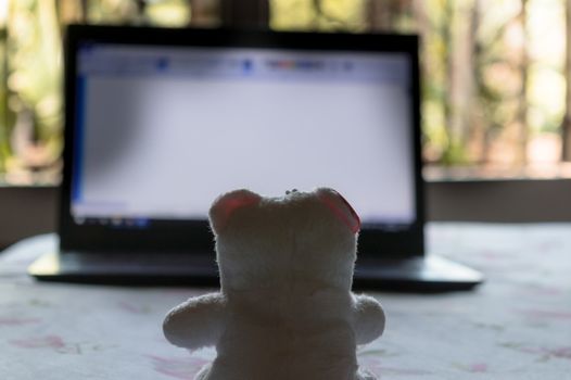 Teddy bear sitting in front of laptop computer device. Still Life. Child using digital technology. Conceptual background concept. Modern childhood education theme. Copy space room for text for massage.