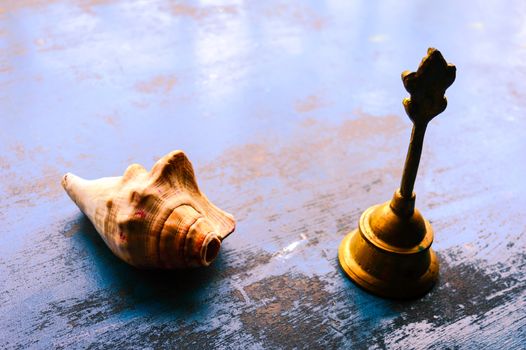 Close up Still Life of antique Conch shell and a bell on rustic floor. Faith, Tradition, Spirituality, Prayer, symbols of peace and Religious Themes. Arts and culture background concept. Copy space room for text for massage.