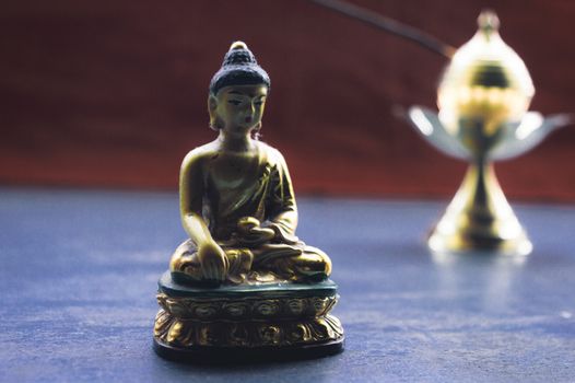 Close up Still Life of antique Meditating Buddha and bell on rustic floor. Faith, Tradition, Spirituality, Prayer, symbols of peace and Religious Themes. Arts and culture background concept. Copy space room for text for massage.