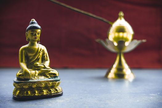Close up Still Life of antique Meditating Buddha and bell on rustic floor. Faith, Tradition, Spirituality, Prayer, symbols of peace and Religious Themes. Arts and culture background concept. Copy space room for text for massage.
