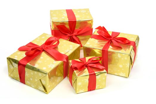 Concept of luxury Christmas gifts - boxes packed in golden paper and tied with a red satin ribbon on a white background