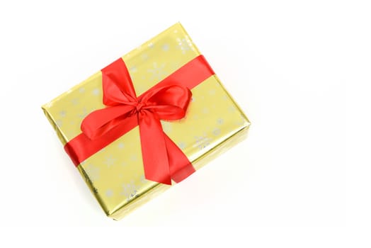 Concept of luxury Christmas gift - a box packed in a golden paper and tied with a red satin ribbon on a white background