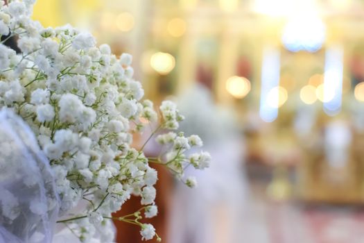 Decoration of wedding flowers against the background of a beautifully blurred church interior with a bokeh effect