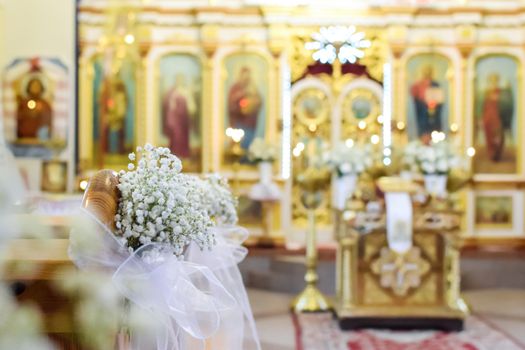 Decoration of wedding flowers against the background of a beautifully blurred orthodox church interior 