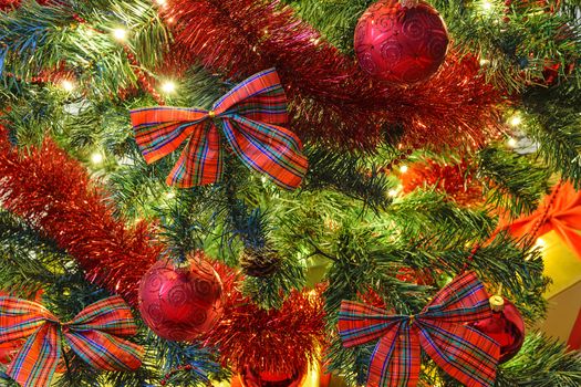 Beautiful Christmas decoration as a background - illumination of lights and red bows and baubles on a Christmas tree in close-up