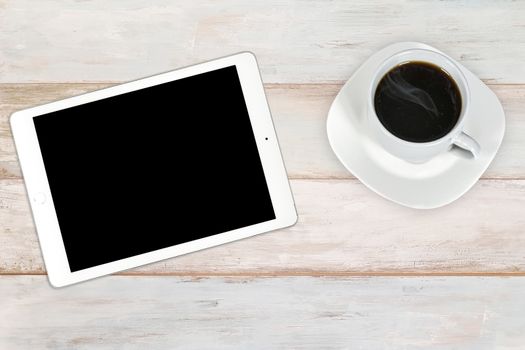 Concept of creative workplace -  modern white and silver digital tablet with cup of coffee on a wooden bright background (high angel view)