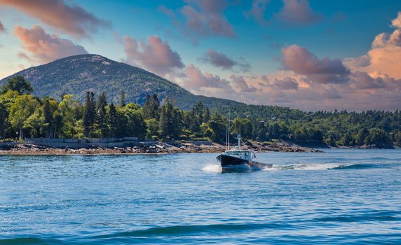 A black fishing boat cutting through blue Maine water