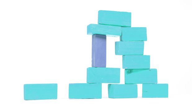 Vintage blue building blocks isolated on white background, one standing out