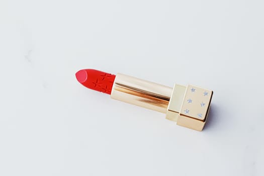 Luxury lipstick in a golden tube on white marble background, make-up and cosmetics concept