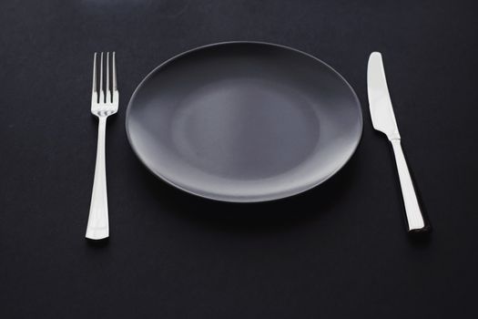 Empty plates and silverware on black background, premium tableware for holiday dinner, minimalistic design and diet concept